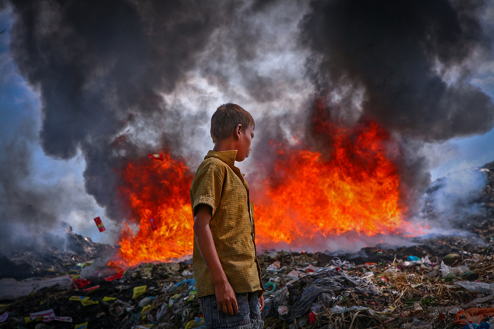 A boy find out any saleable materials at Close to the fire  in The permanent Waste land under Sylhet city corporation. Lalmatia, Sylhet, Bangladesh.