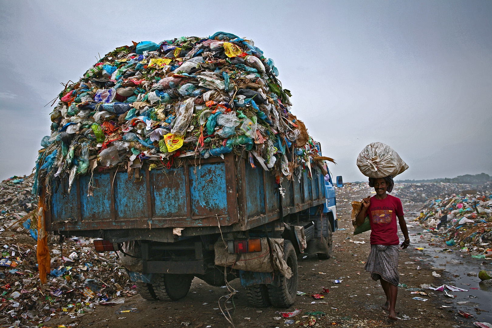 A man is go to market for selling collected materials and another waste carrying trucks are entering. The permanent Waste land under Sylhet City Corporation. Lalmatia, Sylhet, Bangladesh